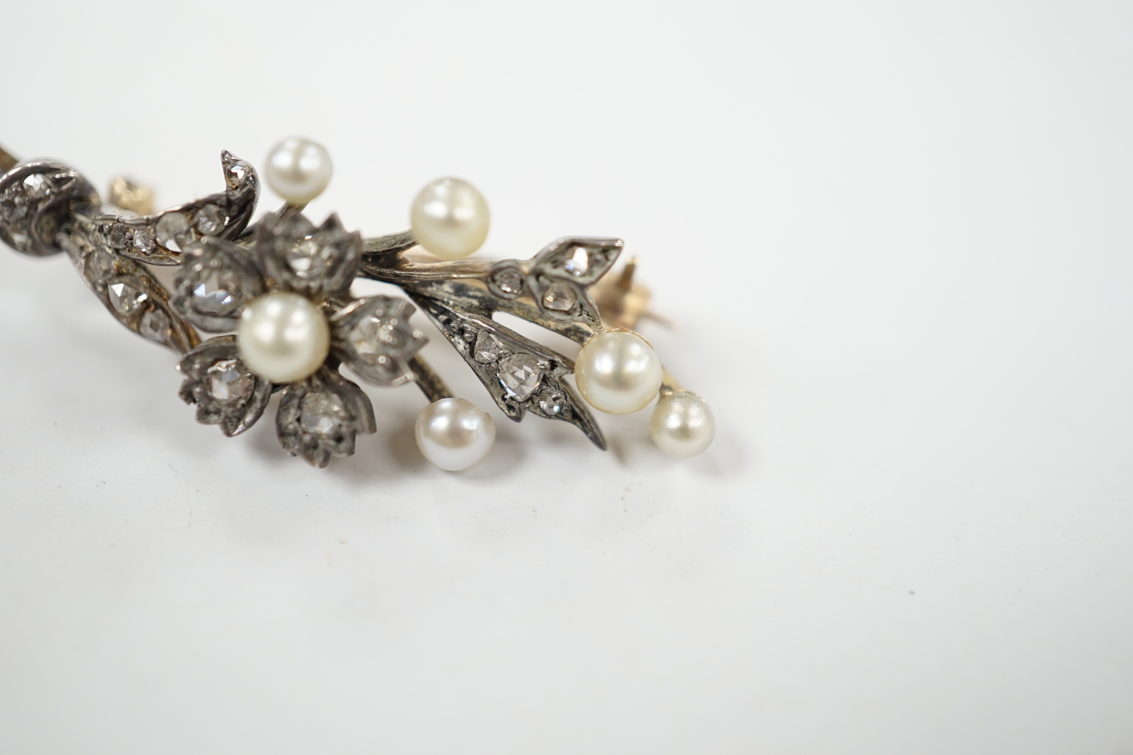 A cased Victorian yellow metal, seed pearl and rose cut diamond set foliate spray brooch, 39mm, gross weight 4.4 grams.
